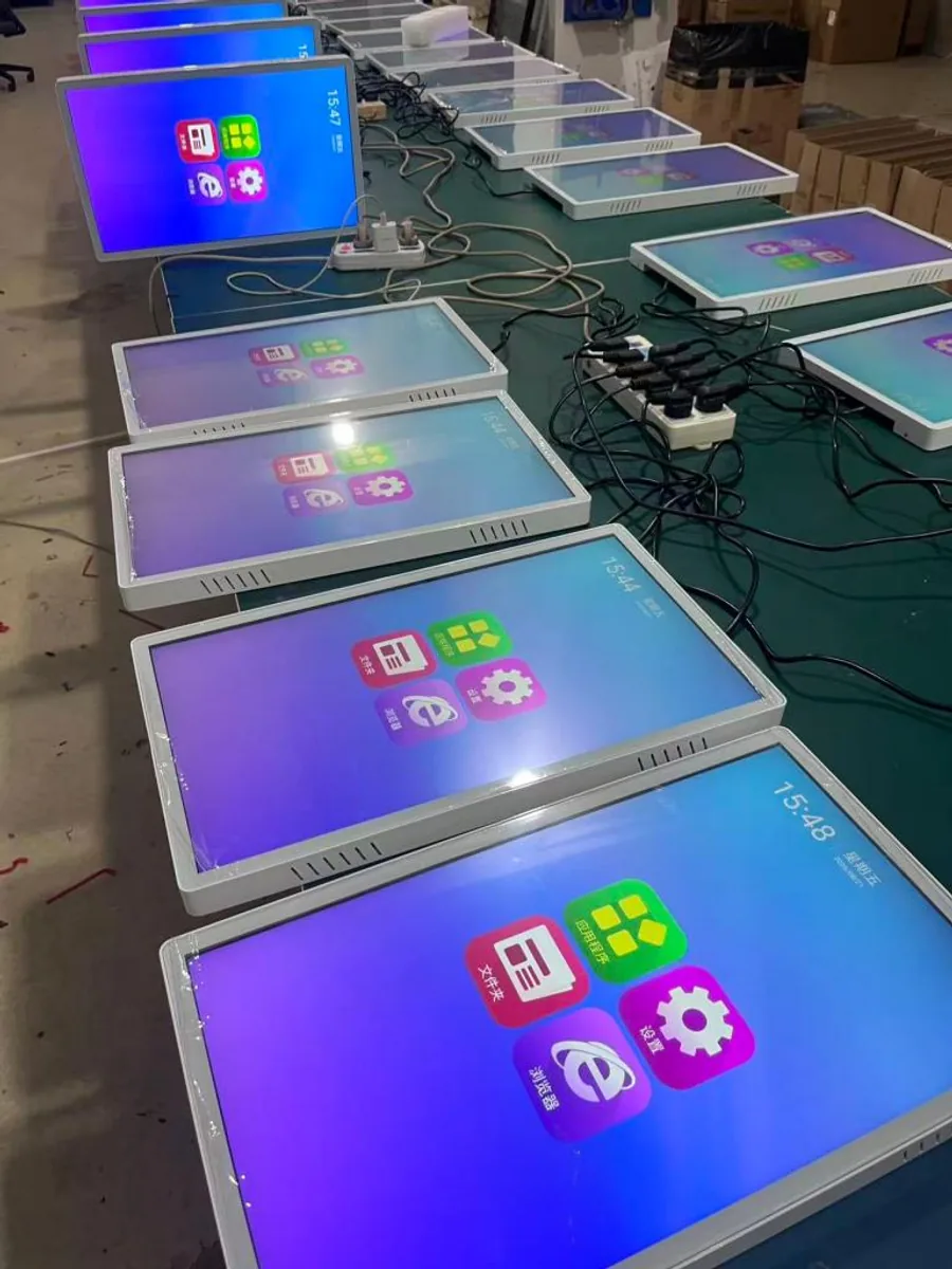 Rows of self-service terminals powered on for ageing and function testing on the production line